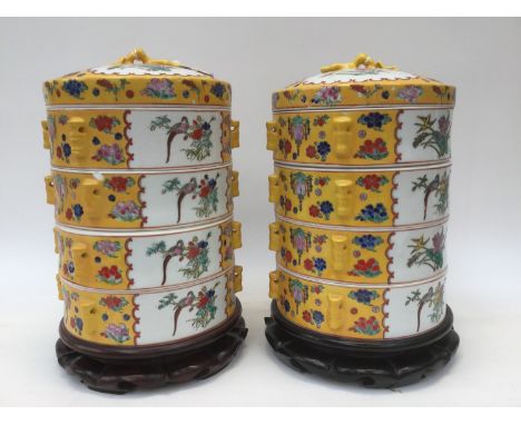 A pair of Chinese ceramic wedding food baskets, each with four tiers and lids on wood stands, yellow ground with enamelled bi