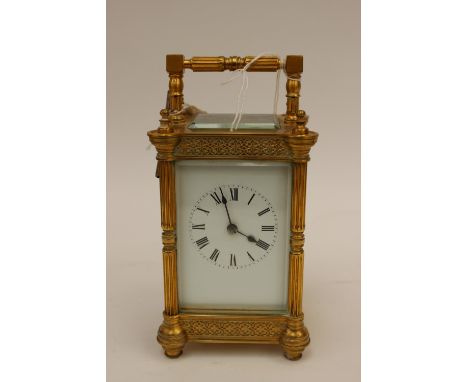 A large brass carriage clock, having Roman numeral white enamel dial, coiled spring gong, the ornate case with fluted column 