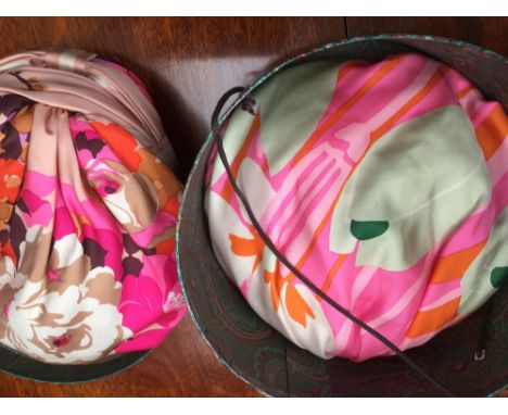 A hat box containing two Christian Dior turban hats - one has a raspberry pink floral detail and is silk - the other has a ro