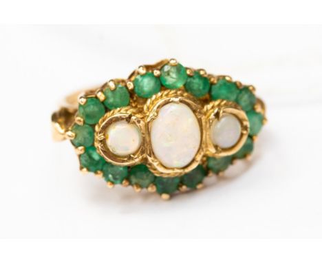 An opal and emerald large dress ring, three oval opals surrounded by a border of round cut emeralds, size O, total gross weig