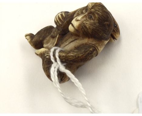 A fine Japanese Meiji period carved ivory netsuke, late 19th Century, of a seated monkey wearing traditional robe with large 