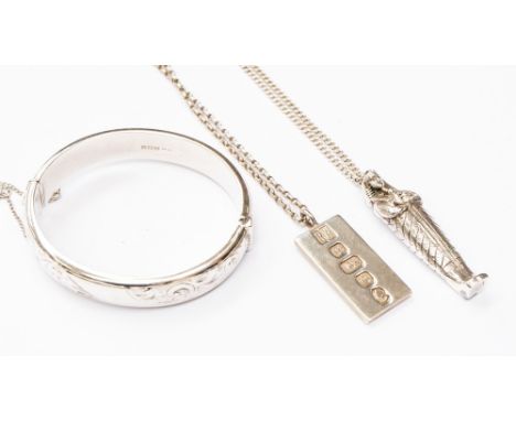 A group of three silver items including an Egyptian pendant and chain, a silver ingot and chain along with a silver bangle 