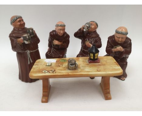 Bretby figurines of four monks drinking ale, one standing, two sat on beer kegs and one sat on books, also a table including 