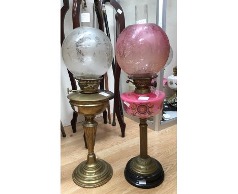 A brass oil lamp with pink reservoir, similar shade and clear chimney; together with another with brass reservoir (2) 