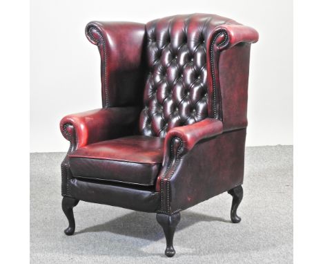 A Thomas Lloyd red leather upholstered button back wing armchair, on cabriole legs