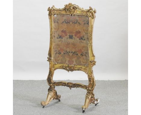 A Victorian embroidered fire screen, with a gilt gesso frame, 107cm high