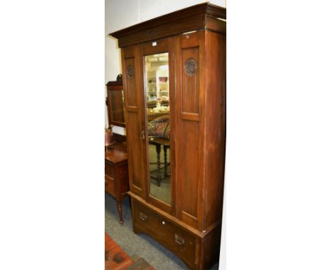 An Art Nouveau mahogany single wardrobe, ogee cornice above central mirror flanked by circular whiplash motif, one long drawe