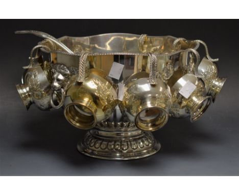 A silver plated punch bowl with eight hanging cups and matched ladle, the bowl decorated with foliate swags and lion mask han