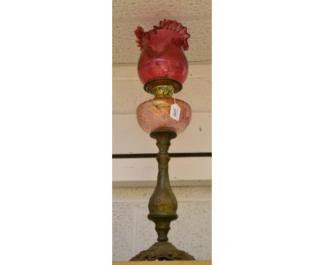 A Victorian style oil lamp, pink reservoir, cranberry glass shade, gilt metal baluster column, cast foot 