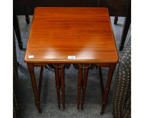 A nest of three teak occasional tables raised on tapering ring turned supports, 48cm sq by 59cm 