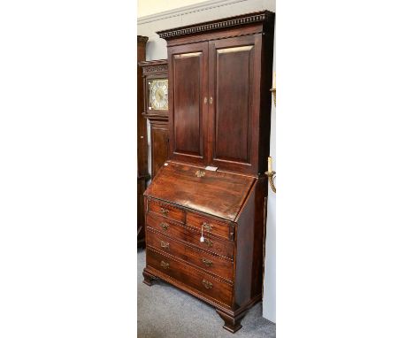 ~ A George III mahogany bureau bookcase, circa 1770, the dentil cornice above panelled cupboard doors enclosing a fitted inte