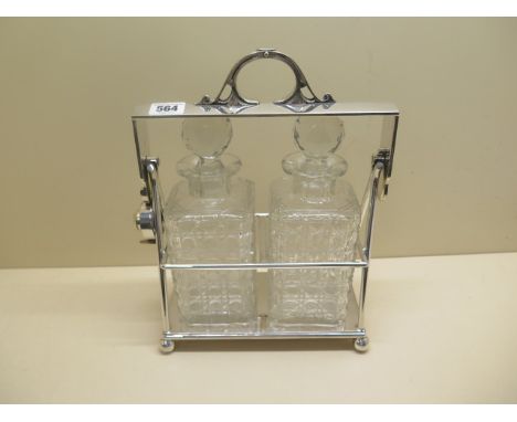 A silver plated two bottle tantalus 32cm tall, 27cm wide, some small chips to bottles otherwise generally good condition 