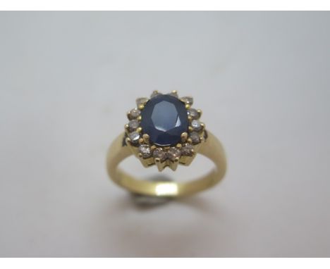 A 14ct yellow gold sapphire and diamond ring - the sapphire measures approx 9mm x 7mm x 4mm - surrounded by 14 small diamonds