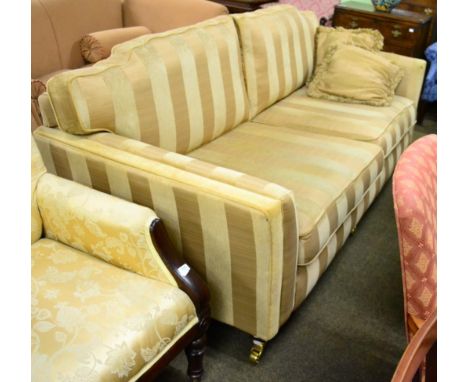 Kirkdale: a three seater sofa upholstered in yellow and gold stripped fabric, modern, raised on three brass capped forelegs w