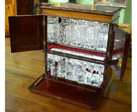 A mahogany table top cocktail cabinet containing four decanters, six whisky tumblers and six sherry glasses 