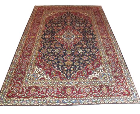 FINE PERSIAN KASHAN CARPET, 354cm x 243cm, ruby pole medallion on a midnight blue field of scrolling vines and palmettes with