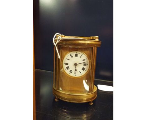 A circa 1900's brass and glass oval shaped carriage clock the dial with Roman numerals (needs attention) one glass panel miss
