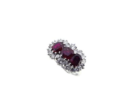 A ruby and diamond triple cluster ring, claw set central cushion shaped ruby, 5.9 x 5.8mm, flanked by two oval faceted rubies
