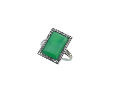 An Art Deco jade and diamond ring, central rubover set rectangular jade, 12.3 x 8.2mm, surrounded by a border of grain set ei