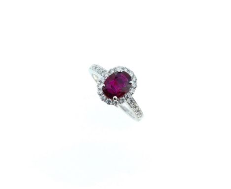 An 18ct gold Burmese ruby and diamond halo style cluster ring, claw set central oval faceted ruby, 7.96 x 5.93mm, surrounded 