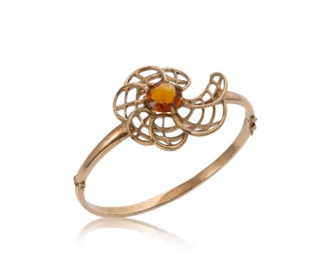 A late 20th century 9ct gold hinged bangle set with a citrine, a stylised pierced flower with a claw set central round facete
