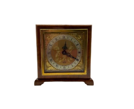 A compact mid-20th century English mantle clock in a square walnut case on raised feet, square brass dial with spandrels and 