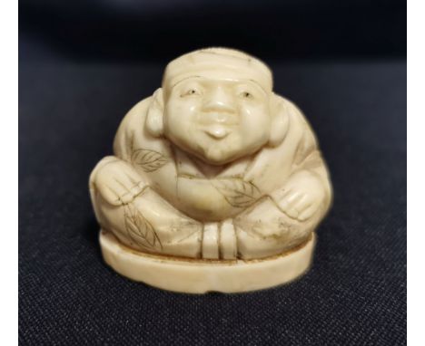 NETSUKE "Hockender Mann", detailreich geschnitzt und unter dem Stand mit großen, rot akzentuierten Schriftkartuschen gemarkt.