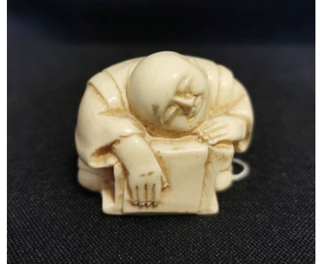 NETSUKE "SCHLAFENDER SCHREIBER"; über seinem Tisch und seiner Arbeit zusammengesunken schlafender Mann im Kimono. Detailreich