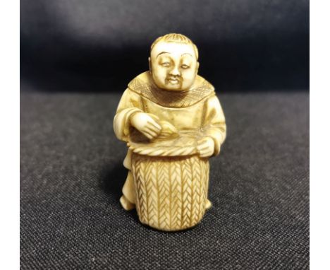 NETSUKE "Händler / Bauer", detailreich und auch unter dem Stand geschnitzter Händler mit Korb, eine Frucht haltend; revers mi