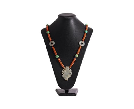 A CARVED JADE AND CORAL BEAD PENDANT NECKLACE The celadon jade pendant plaque, Qing Dynasty, carved as a boy with lotus, late