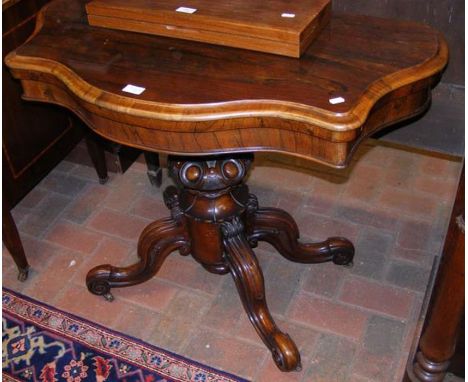 A 19th century rosewood fold over games table on shaped support