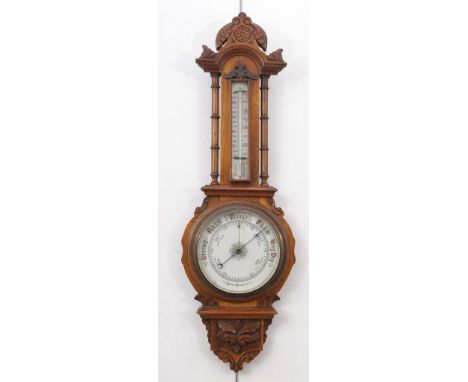 A Victorian oak aneroid wheel barometer 
With a 19cm ceramic register with blued hands and gilt pointer above a thermometer t