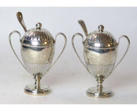 A pair of George V silver condiments 
Each of the stepped circular bases, rising to an ovoid body with fluted design, surmoun