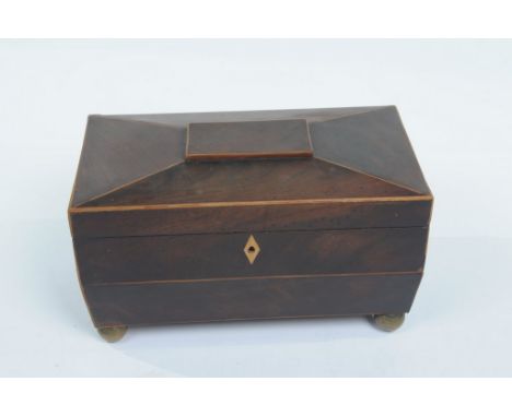A Regency mahogany and inlaid sarcophagus tea caddy.  The hinged triangular top centred with a rectangular panel enclosing tw