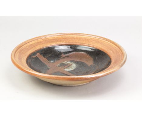 JOHN LEACH (1939-2021) for Muchelney Pottery; a stoneware platter, the well covered in tenmoku glaze with wax resist decorati