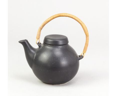 Arabia, Finland; a stoneware teapot with cane handle covered in black glaze, pottery stamp, height 18cm (including handle).Ad