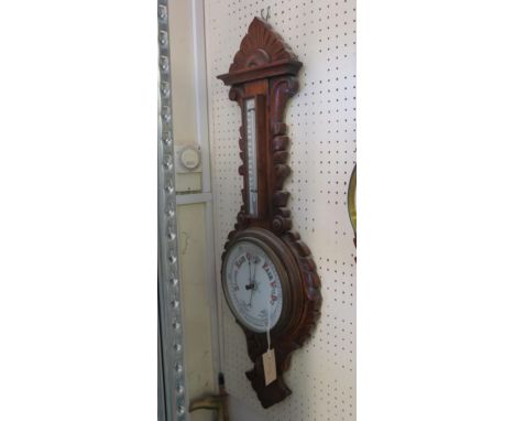 A late Victorian wheel barometer, printed ceramic barometer and thermometer dials, oak case carved with acanthus leafage, 35i