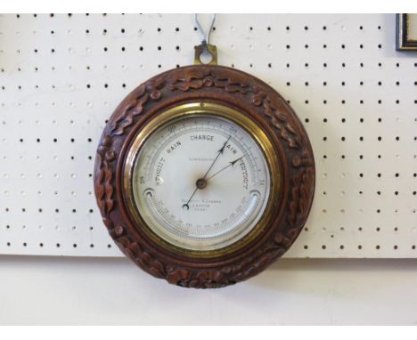 An early 20th century aneroid barometer, dial signed Negretti & Zambra, circular oak case carved with oak leaves and acorns, 