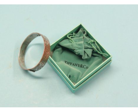 A Tiffany & Co. engraved silver bangle, in original packaging, and one other engraved silver bangle
