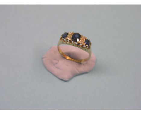 An 18ct. gold engagement ring, three sapphires and four diamond chips in half-hoop claw setting, size L/M, Birmingham 1917 