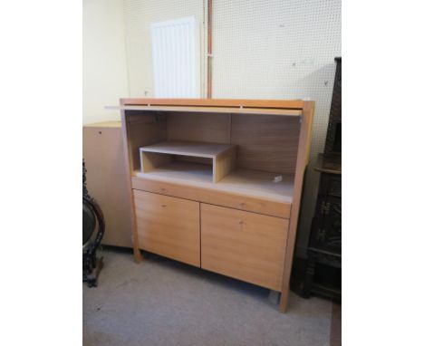 A modern light oak student's desk unit, rising upper door enclosing space for computer storage, cupboard base with single dra