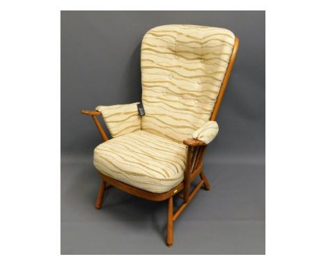 An upholstered blond Ercol chair with original labels, 42in high to back 