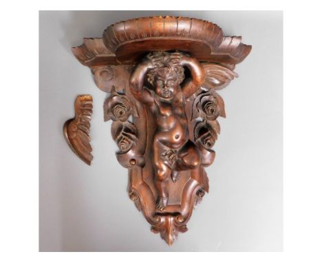 A 19thC. carved walnut wall bracket with winged cherub decor, one wing detached, 15.75in high x 14in wide x 8in deep