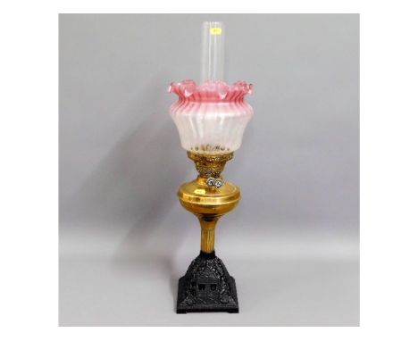 A Victorian brass oil lamp with frosted, cranberry tipped shade &amp; cast iron base, 26in tall