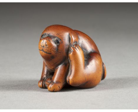 EIN HOLZGESCHNITZTES NETSUKE EINES WELPEN Japan, 18./19. Jahrhundert Holz. H. 3 cm. Das Netsuke ist als ein sitzender Welpe g