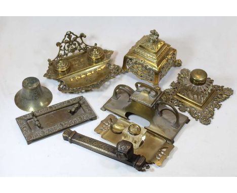 A Victorian brass inkwell, the hinged square cover surmounted by a seated female figure, the body with pierced floral decorat