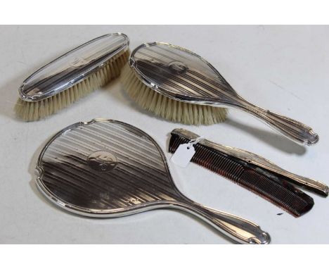 A George V silver backed four piece dressing table set to include hand mirror, hand brush, hair brush and comb (4)