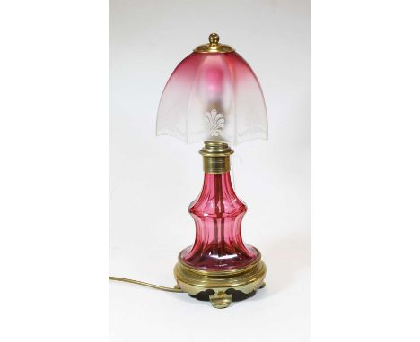 A 20th century rose glass and brass table lamp, the umbrella shade with etched anthemion decoration above a faceted and doubl