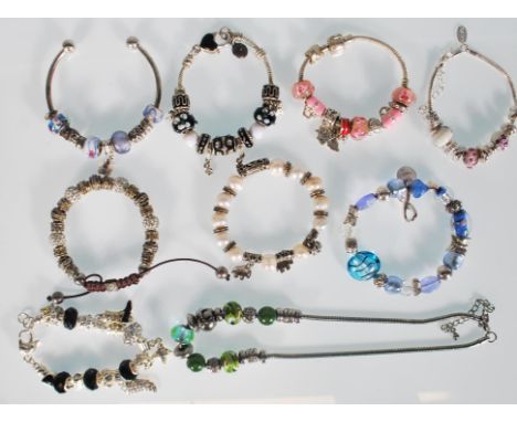 A group of silver white metal bracelets to include an open bangle bracelet, four snake chain bracelets with charms, a snake c