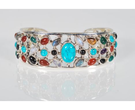 A substantial and unusual large silver bangle being set with lozenge and cabochon amethyst, sapphires, garnet and turquoise c